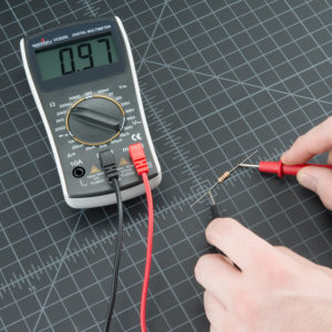 Przedłużenie do pomiaru elektrycznego z multimetrem i rezystorem na czarnym tle.